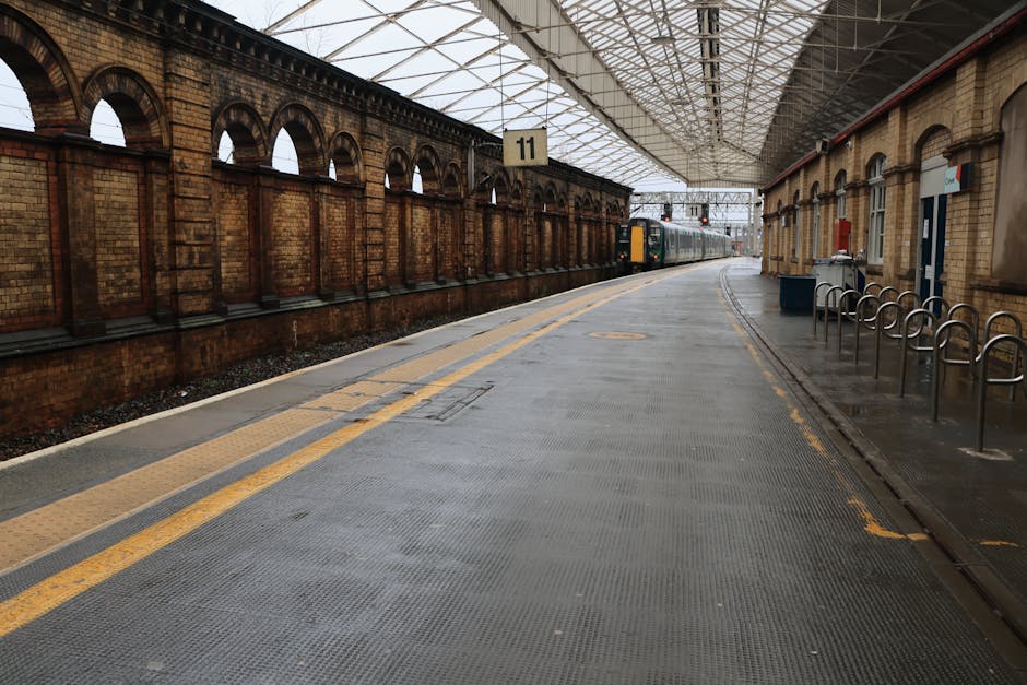 Outside view of Crystal Palace station platform in SE19 showing a modern, curved glass and metal shelter with seating areas on the left, where two passengers are seated, and a busy platform on the rig
